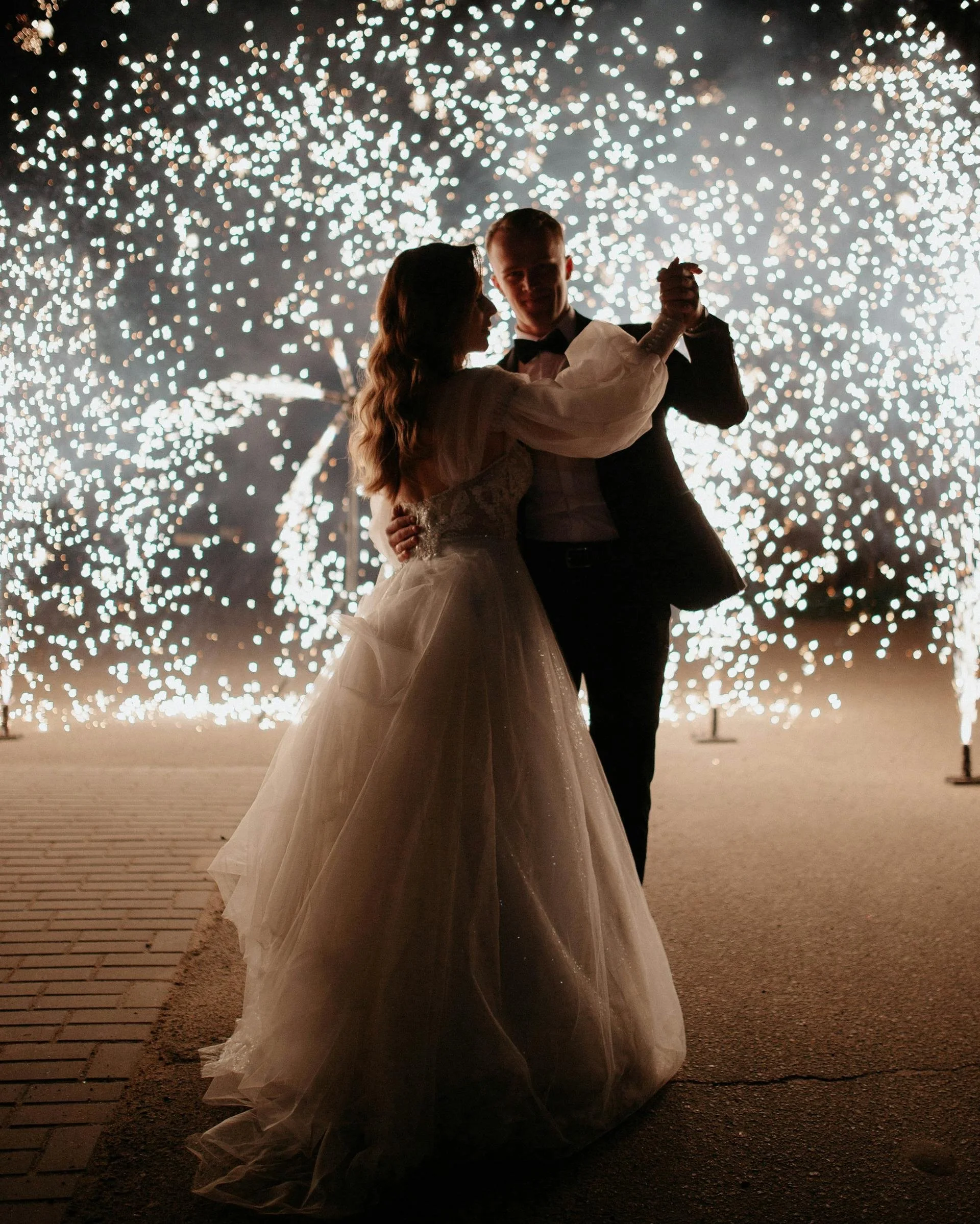 couple dance in the dark surrounded by fire sparklers