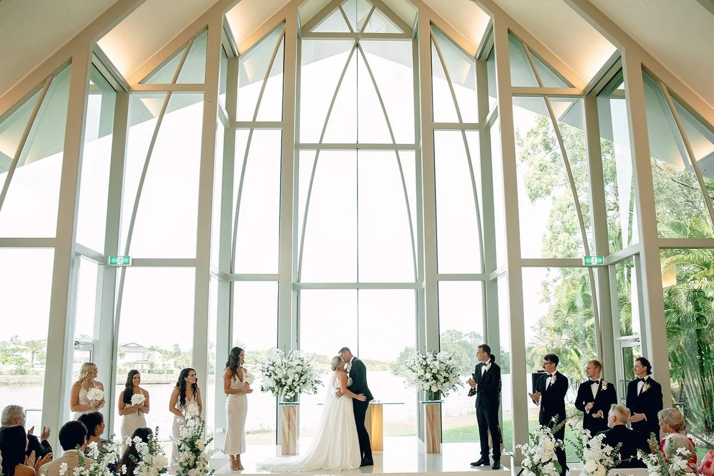 wedding couple kissing at the altar in a big glass chapel