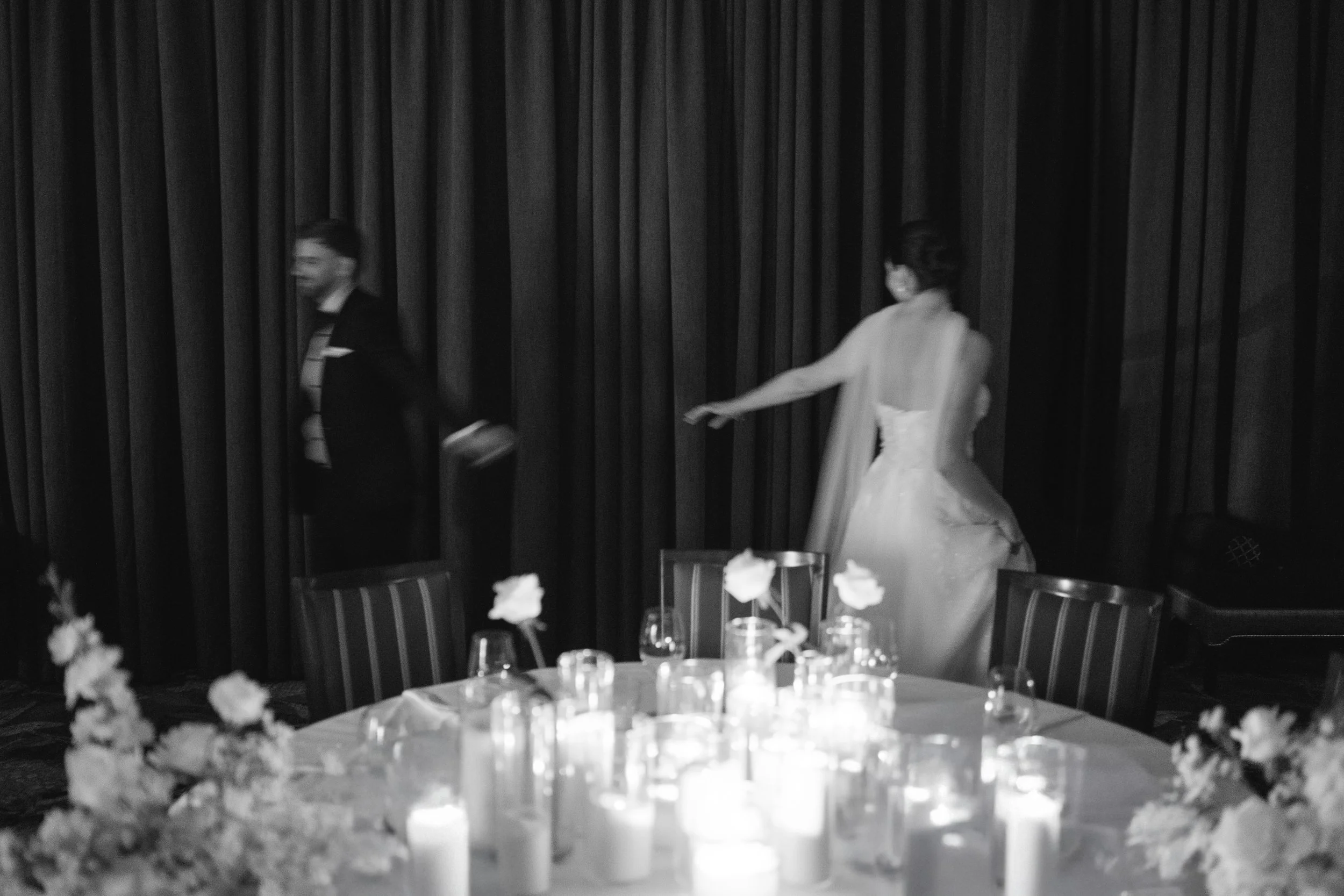 newlyweds walking away from each other with a table of candles and roses in the foreground
