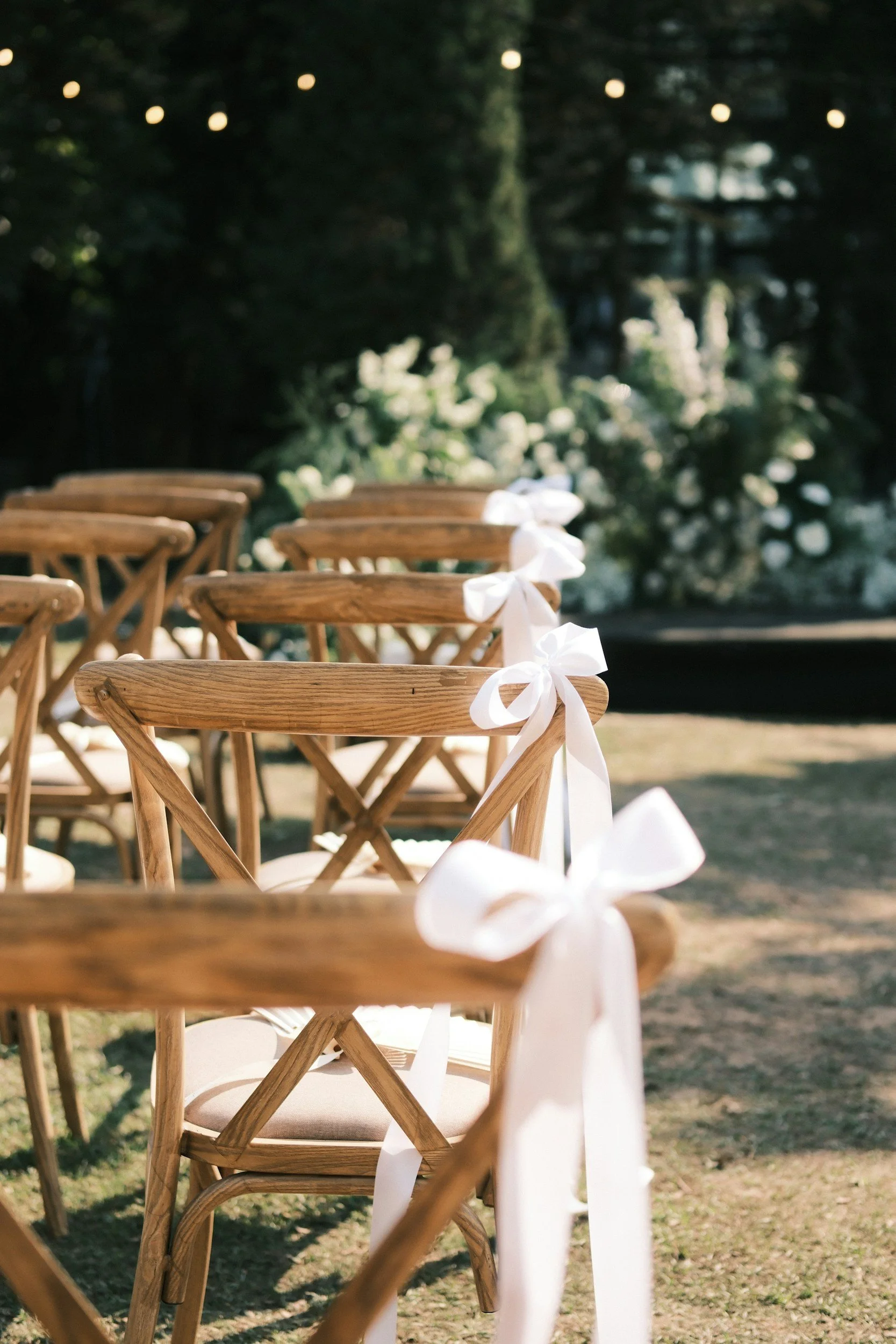 oak crossback chairs in rows with white bows tied to the ends