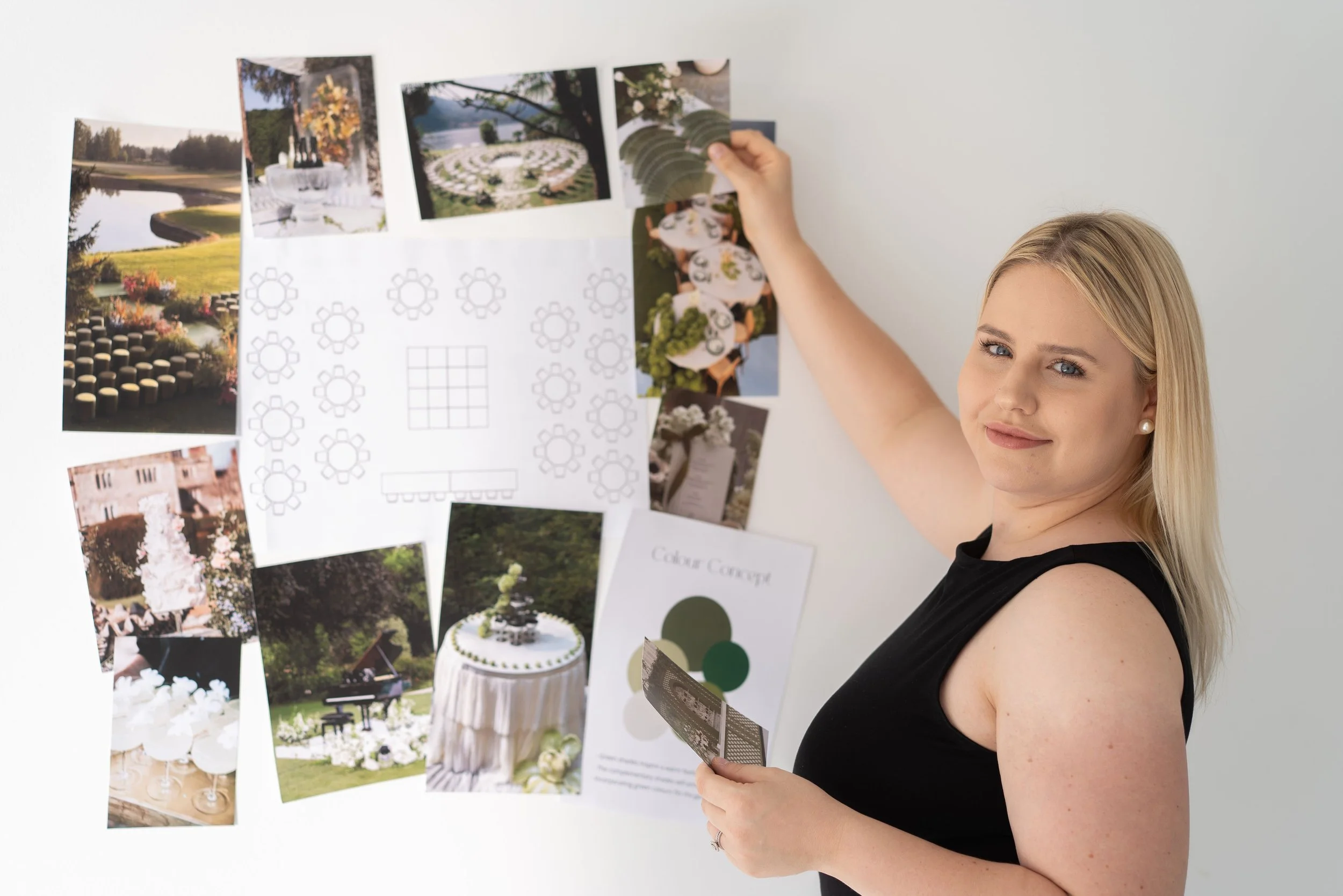 wedding planner smiling at camera while putting inspiration images up on a wall