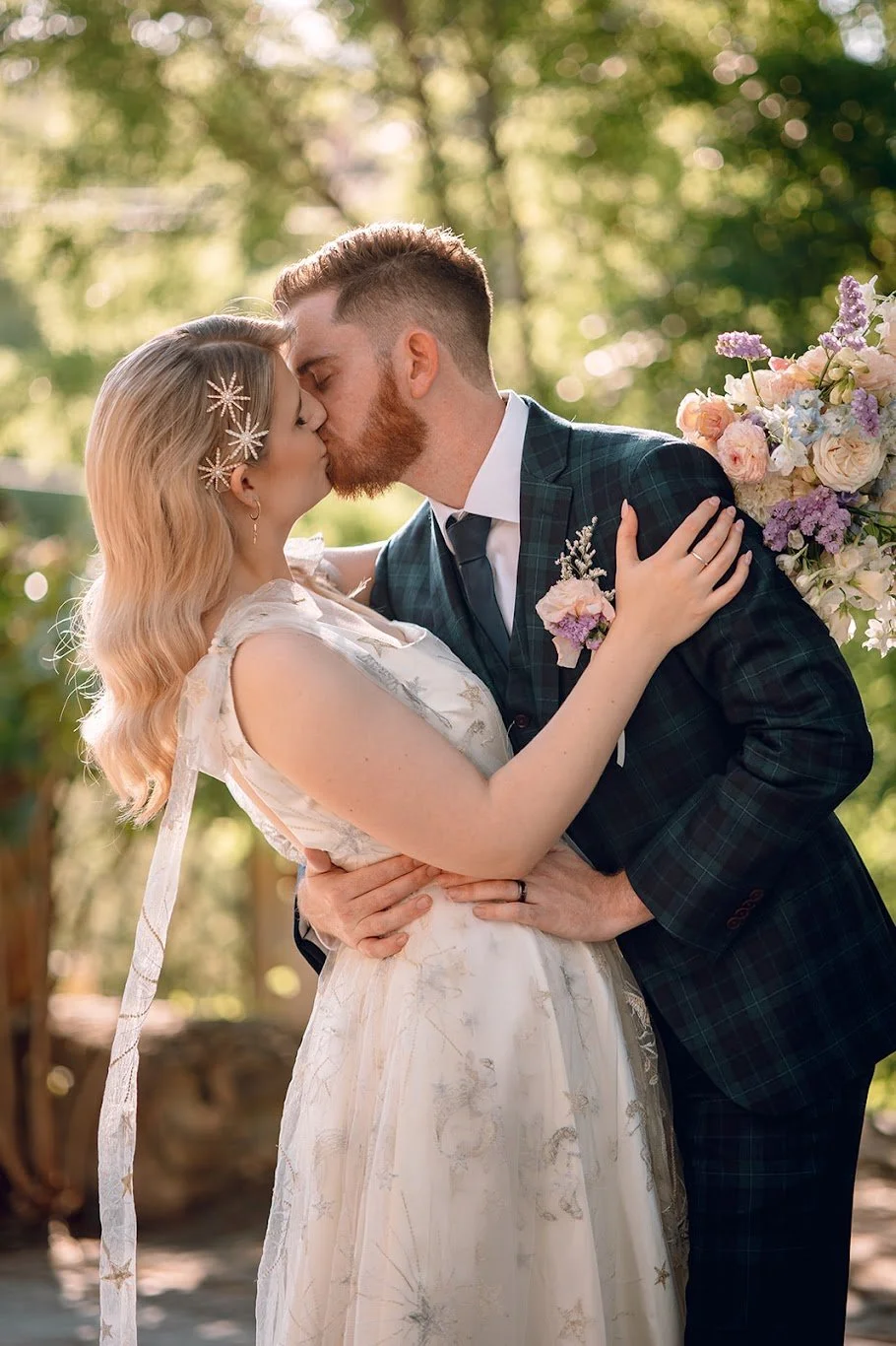 A newly married couple kissing next to some flowers